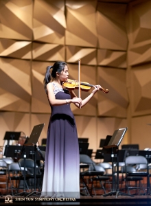 Already changed for the performance, violin soloist Fiona Zheng takes advantage of a final opportunity to practice on stage.